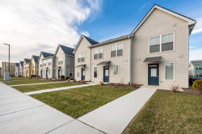 a row of houses with white siding and green grass at Legacy Pointe at Poindexter Apartments & Townhomes