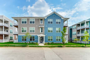 an apartment building with blue and gray facade on a sunny day