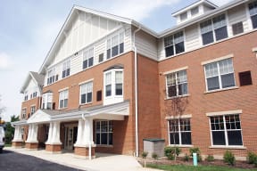 a brick apartment building with white columns and a porch