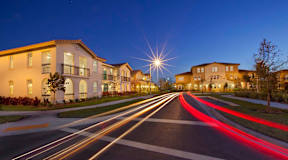 A long exposure shot of a street at dusk with light trails from moving vehicles.
