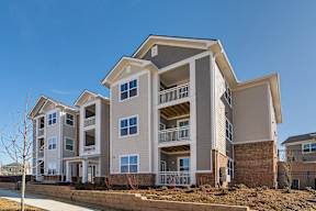 A modern apartment building with multiple balconies and a clear blue sky.
