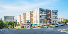 A large apartment building with a parking lot in front.