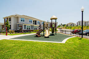 A playground with a slide and a swing set in front of a building.