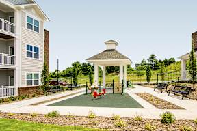 A gazebo is surrounded by benches in a park-like setting.
