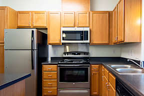 A kitchen with wooden cabinets and a stainless steel refrigerator.