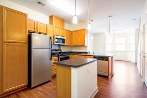 A kitchen with wooden cabinets and a stainless steel refrigerator.