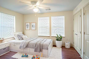 A bedroom with a bed, a ceiling fan, and a window with blinds.