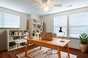 A room with a desk, laptop, and bookshelf.