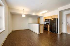 A kitchen with a black refrigerator and wooden cabinets.