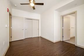 A room with a ceiling fan and wood flooring.