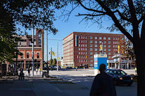 A man is walking on the sidewalk in front of a building.