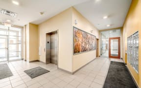 the lobby of a building with elevators and a large painting on the wall