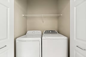 a washer and dryer in a laundry room with white cabinets and a shelf
