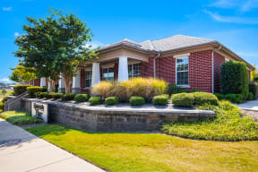 the front of a brick house with a lawn and a stone retaining wall