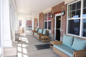 a porch with furniture and a brick wall