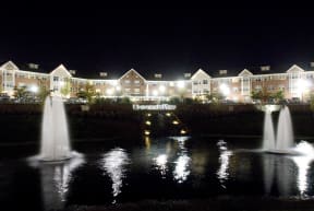 the front of the hotel at night with fountains