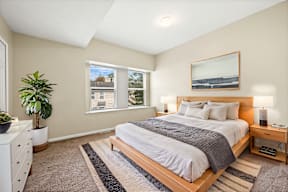 A bedroom with a large bed and a painting on the wall.
