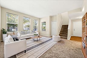 A living room with a white couch and a striped rug.