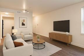 A living room with a white couch, a black television, and a wooden cabinet.