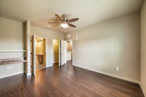 a empty living room with a ceiling fan and wood floors