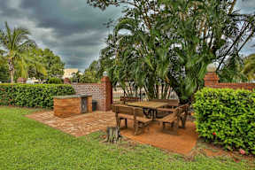 A patio with a table and chairs surrounded by greenery.