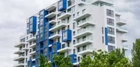 A tall residential building with balconies and windows.