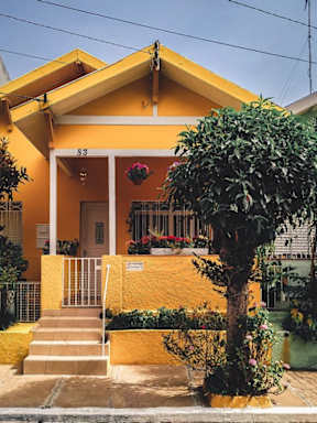 A yellow house with a tree in front.