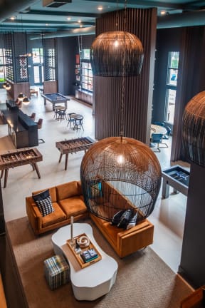 a room with a large bird cage hanging from the ceiling and a lobby with furniture