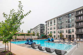 a swimming pool with lounge chairs in front of apartment buildings
