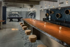 a long bar with stools in a room with a pool table
