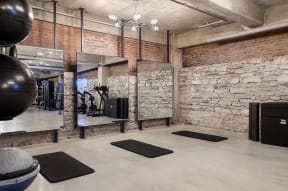 the gym has exposed brick walls and a large exercise ball and rugs