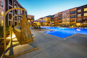a swimming pool with lounge chairs and umbrellas in front of an apartment building