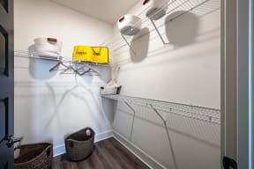 a walk in closet with white walls and a yellow box on a wire shelf