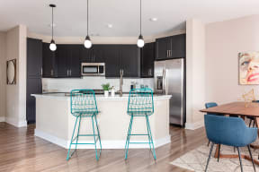 an open kitchen and dining area with bar stools in front of a kitchen island