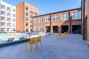 a pool area with yellow chairs in front of a brick building