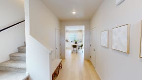 a hallway with stairs and a dining room with a table and chairs