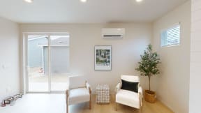 a living room with two white chairs and a tree in the corner