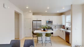 a kitchen with white cabinets and a table with three stools