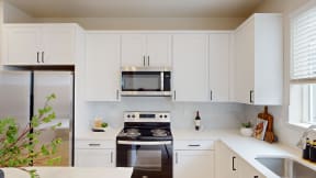 a white kitchen with stainless steel appliances and white cabinets