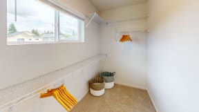 a walk in closet with hooks and baskets and a window