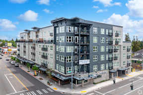 A street view of a multi-story building with a balcony on the top floor.
