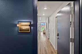 a hallway with a blue door with a door sensor on it at Hue Apartments, Redmond , WA 98052