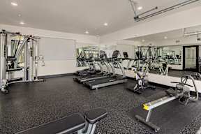 A gym with a variety of equipment including treadmills, weights, and a bench.