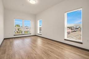 Empty room with wooden floors and two windows.