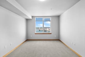 an empty room with a window overlooking a body of water