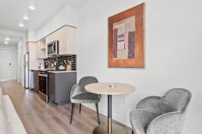 a living room with a table and two chairs and a kitchen with a stove at Hue Apartments, Redmond , WA