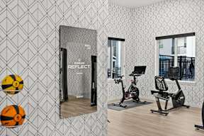 A gym with a mirror, a ball, and a treadmill.
