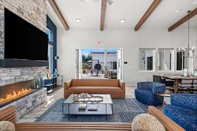 A modern living room with a stone fireplace and a view of the backyard.