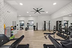 A gym with a variety of equipment including treadmills, weights, and exercise machines.