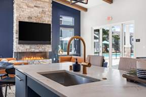 A modern kitchen with a stone fireplace and a large island.
